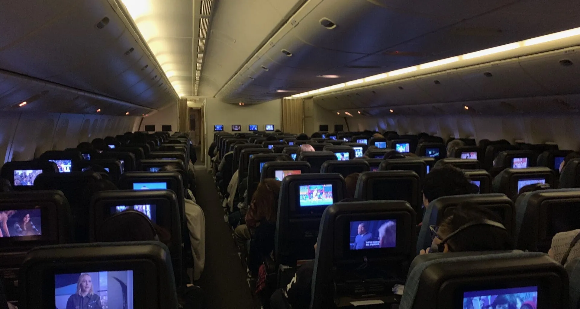 a group of people sitting in an airplane with monitors