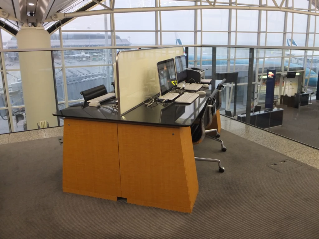 a desk with computers and a large screen