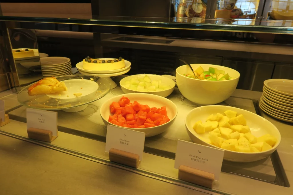 a display case with plates of fruit and desserts