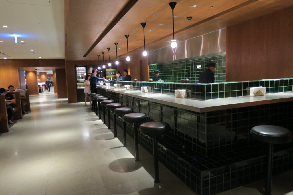 a long bar with stools and people standing in front of them