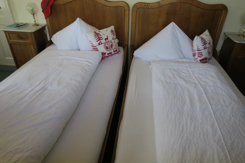 two beds with white sheets and pillows