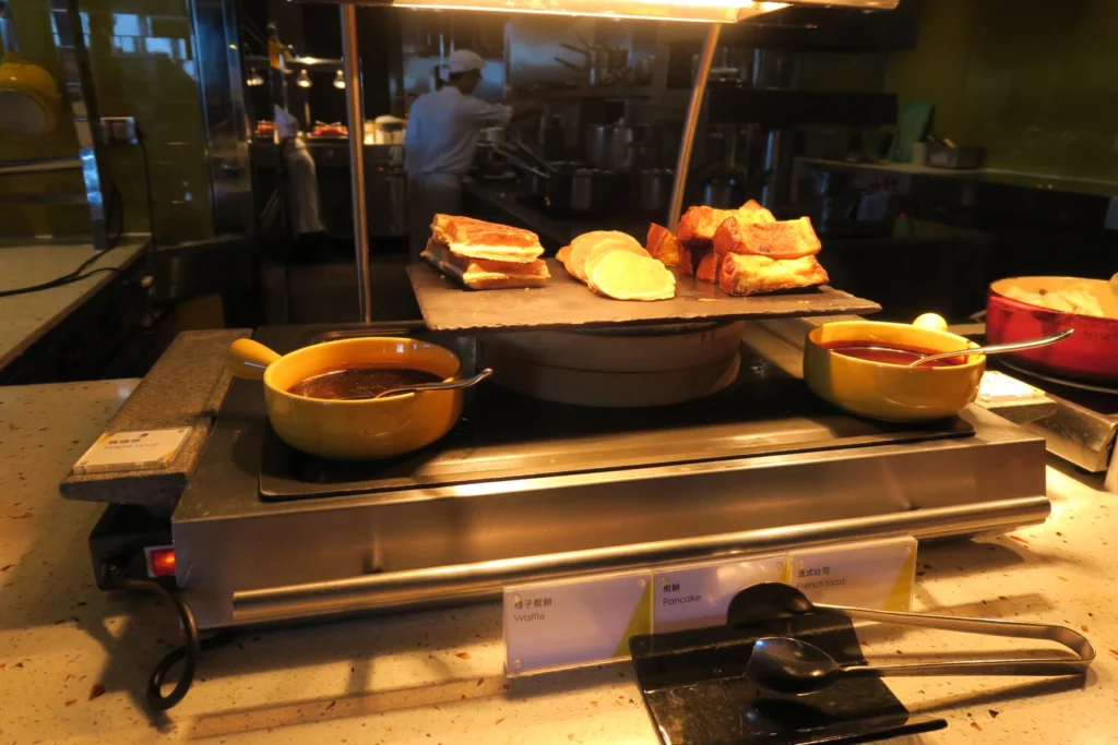 food on a stove with a chef in the background