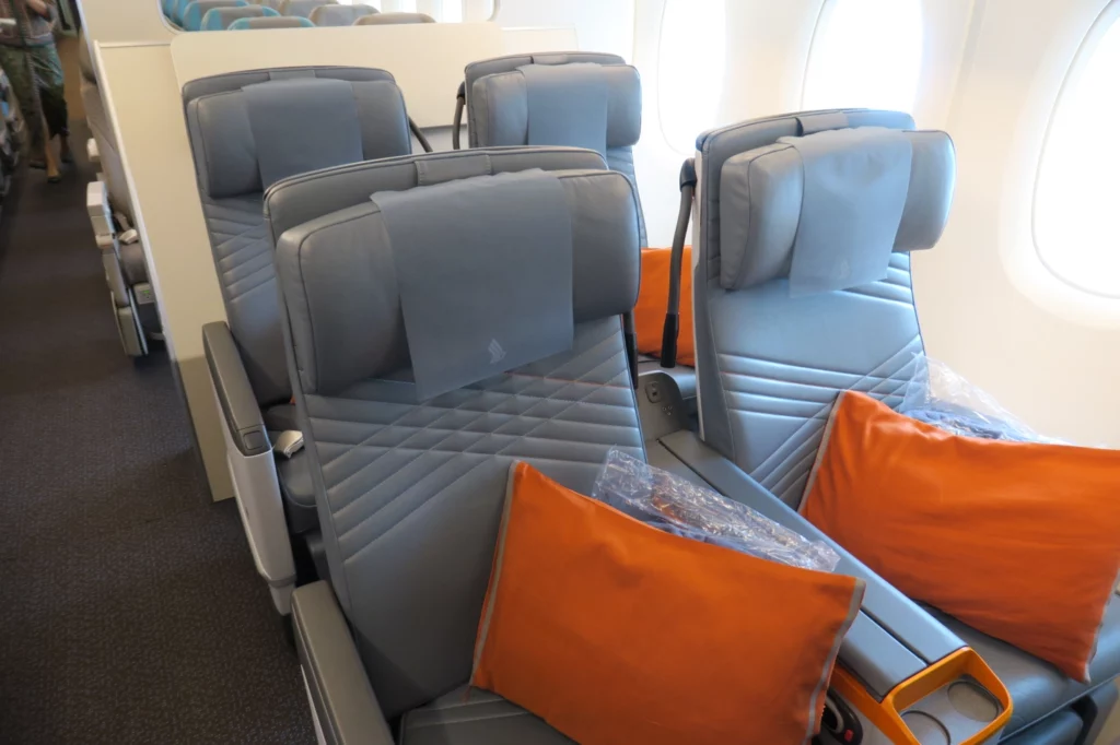 a row of grey seats with orange pillows