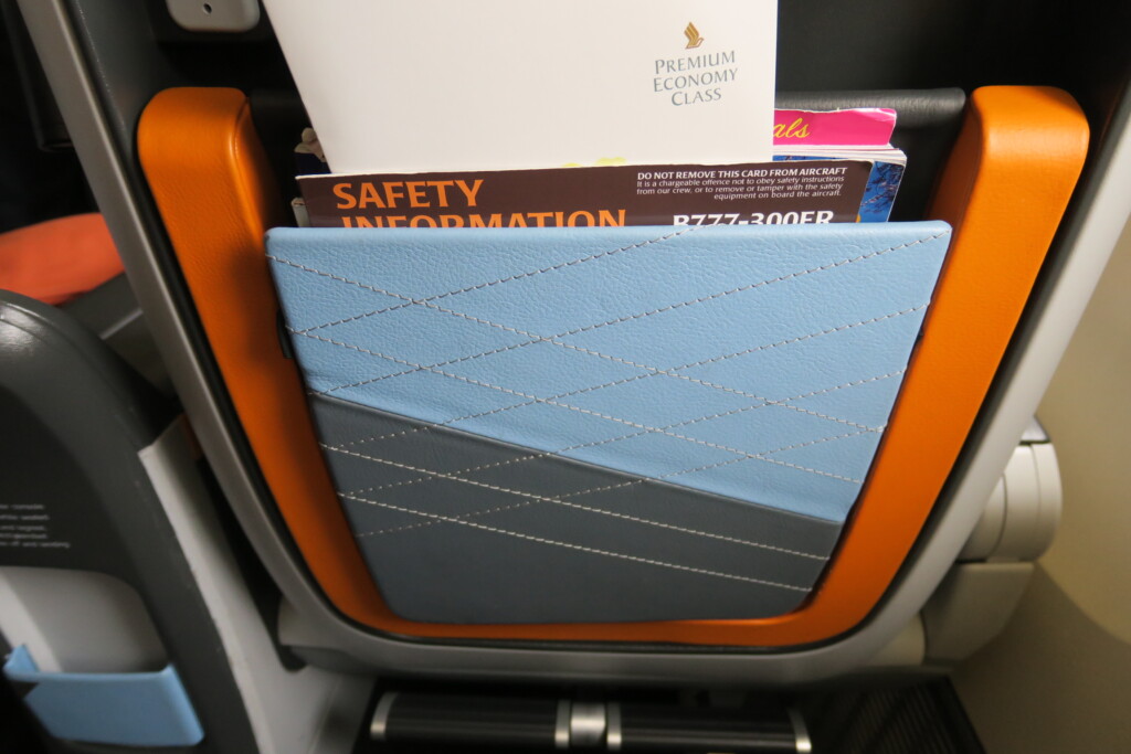 a blue and grey folder in a pocket of an airplane