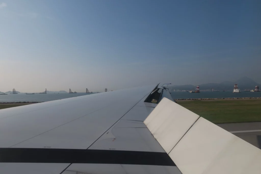 an airplane wing with water and land in the background