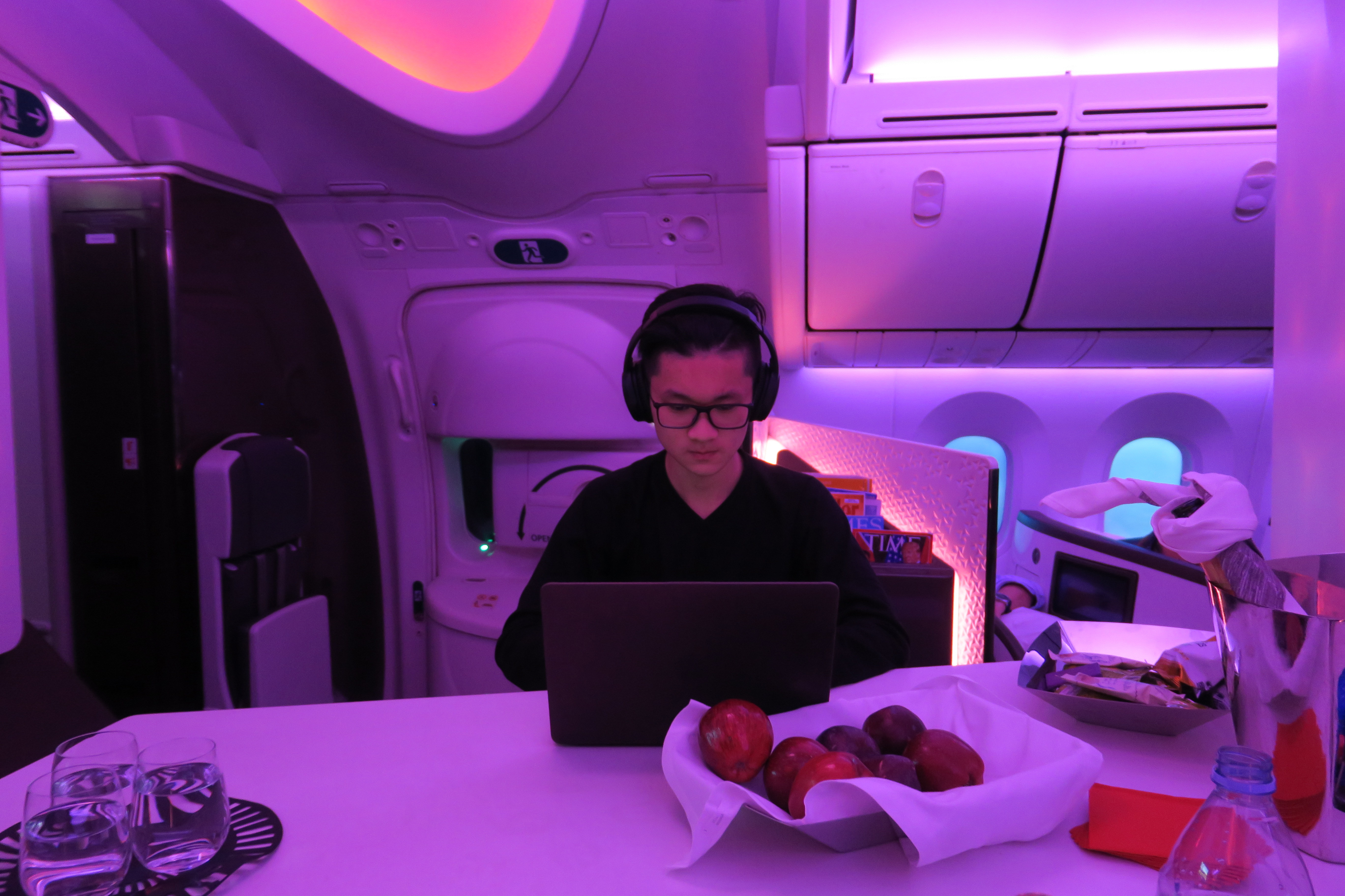 a person sitting at a table with a laptop and fruit in front of them