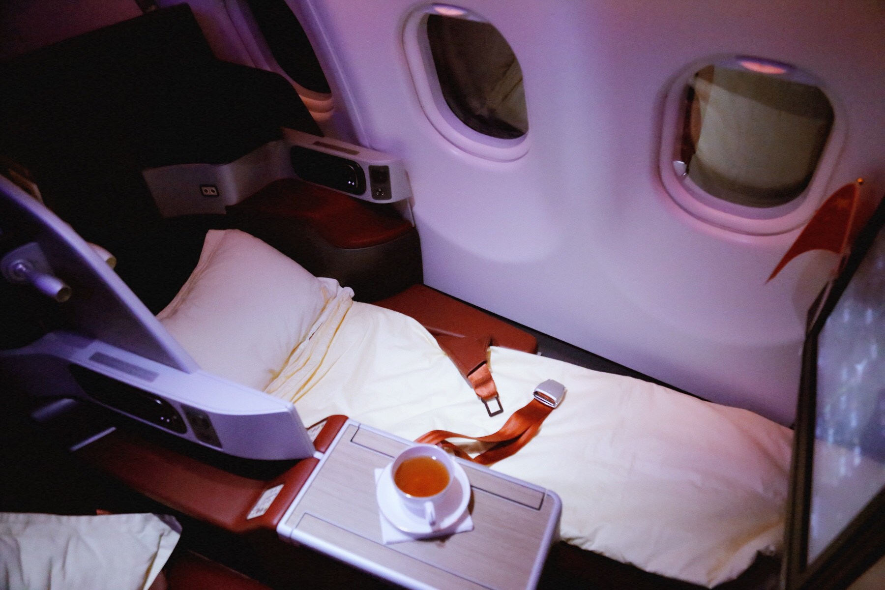 a seat in a plane with a cup of tea and a seat belt