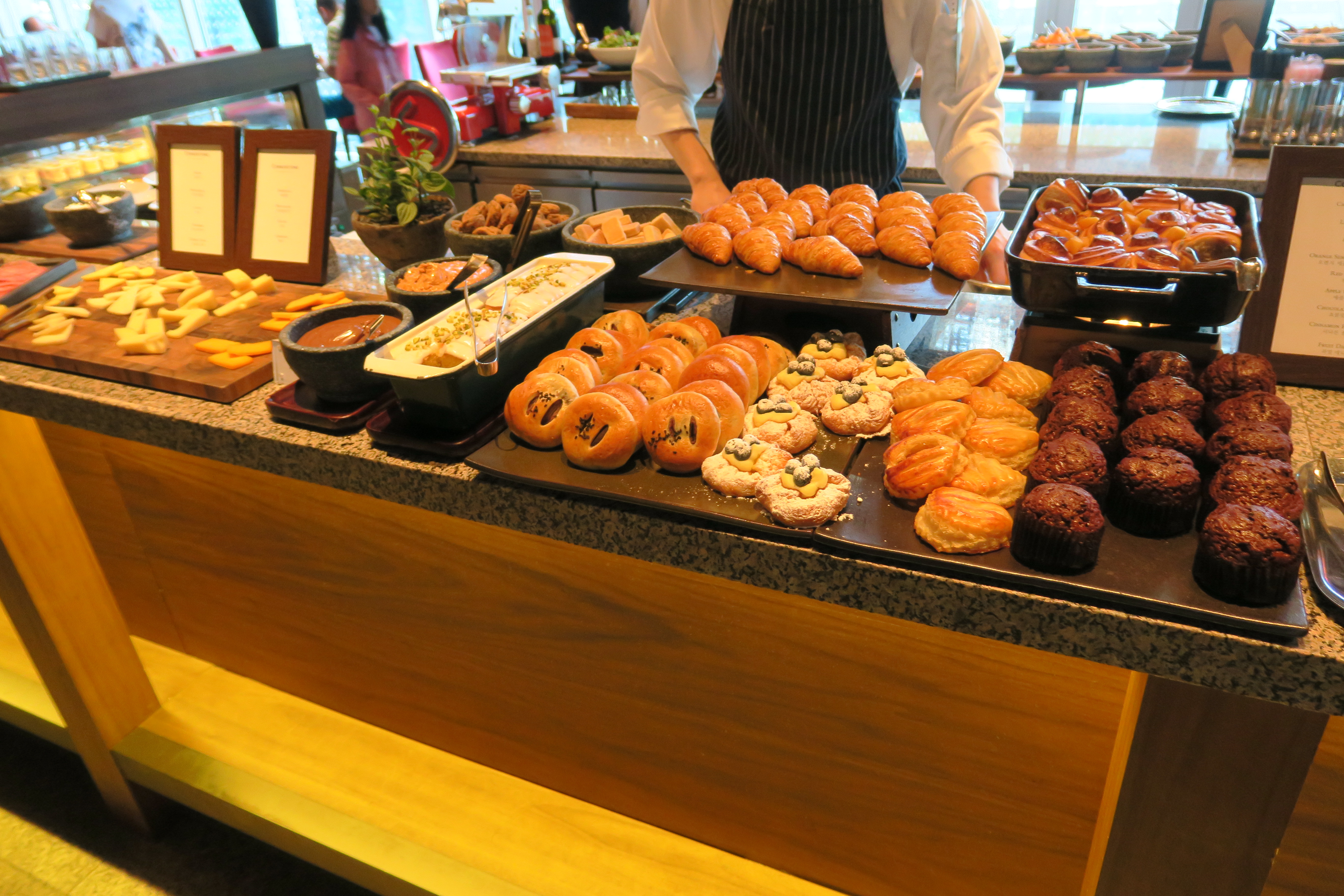 a person standing behind a counter with pastries