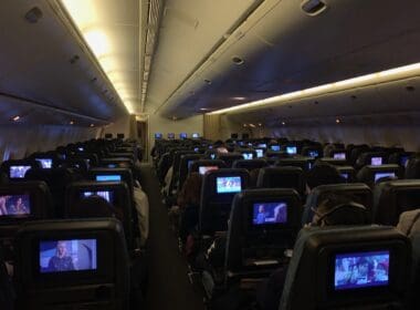 a group of people sitting in an airplane with monitors