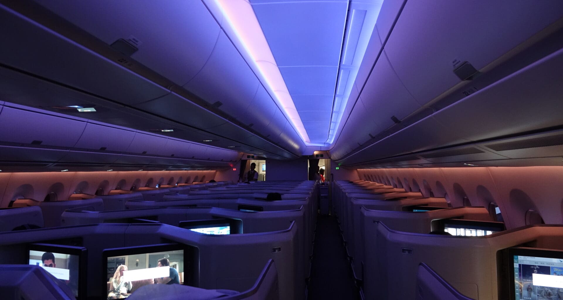 inside an airplane with rows of seats and a person standing in the back