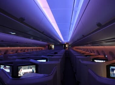 inside an airplane with rows of seats and a person standing in the back