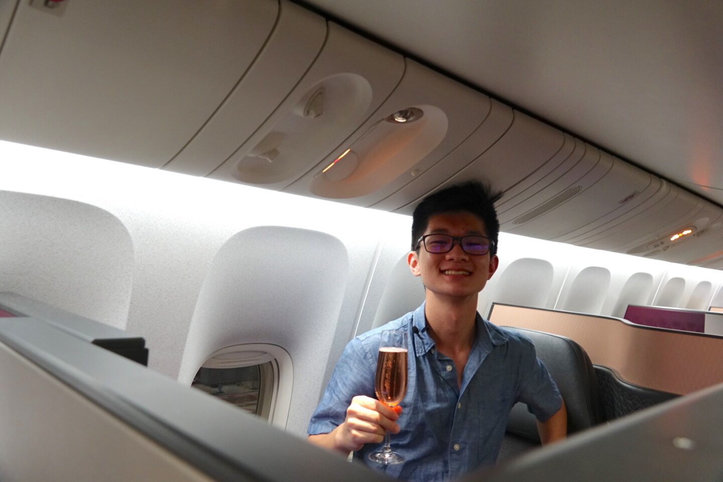 a man sitting in an airplane holding a glass of champagne