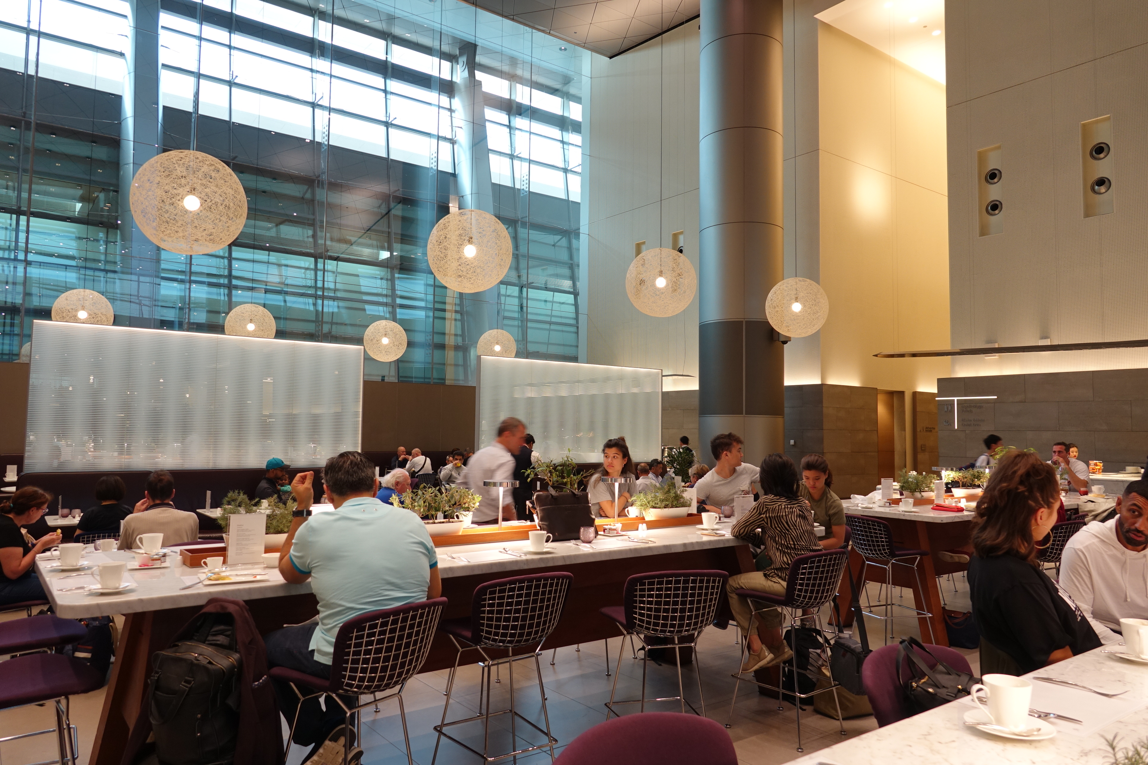 a group of people sitting at tables in a room with lights from ceiling