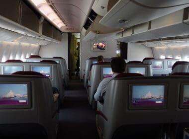 people sitting in an airplane with a television on the back