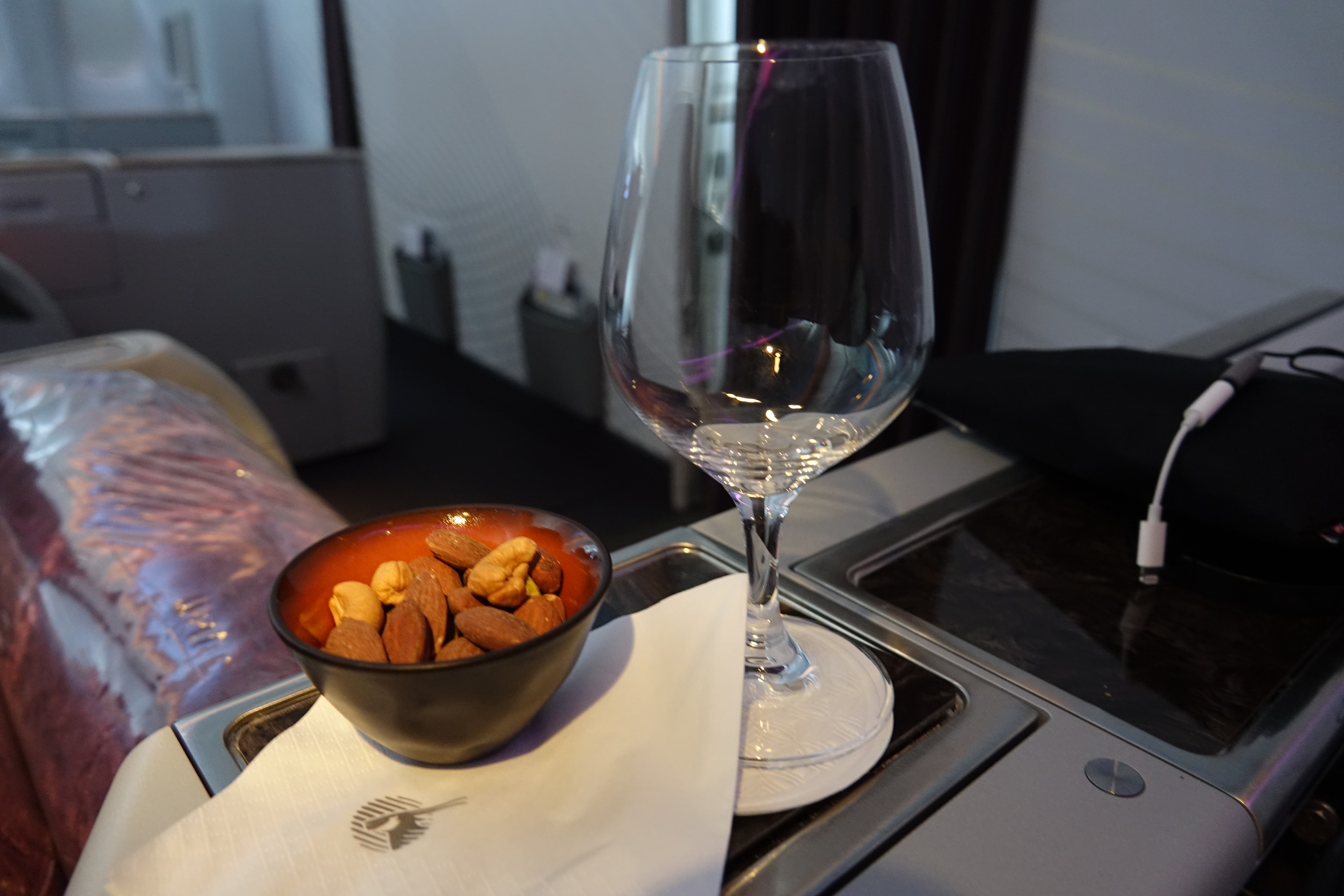 a bowl of nuts and a wine glass on a tray