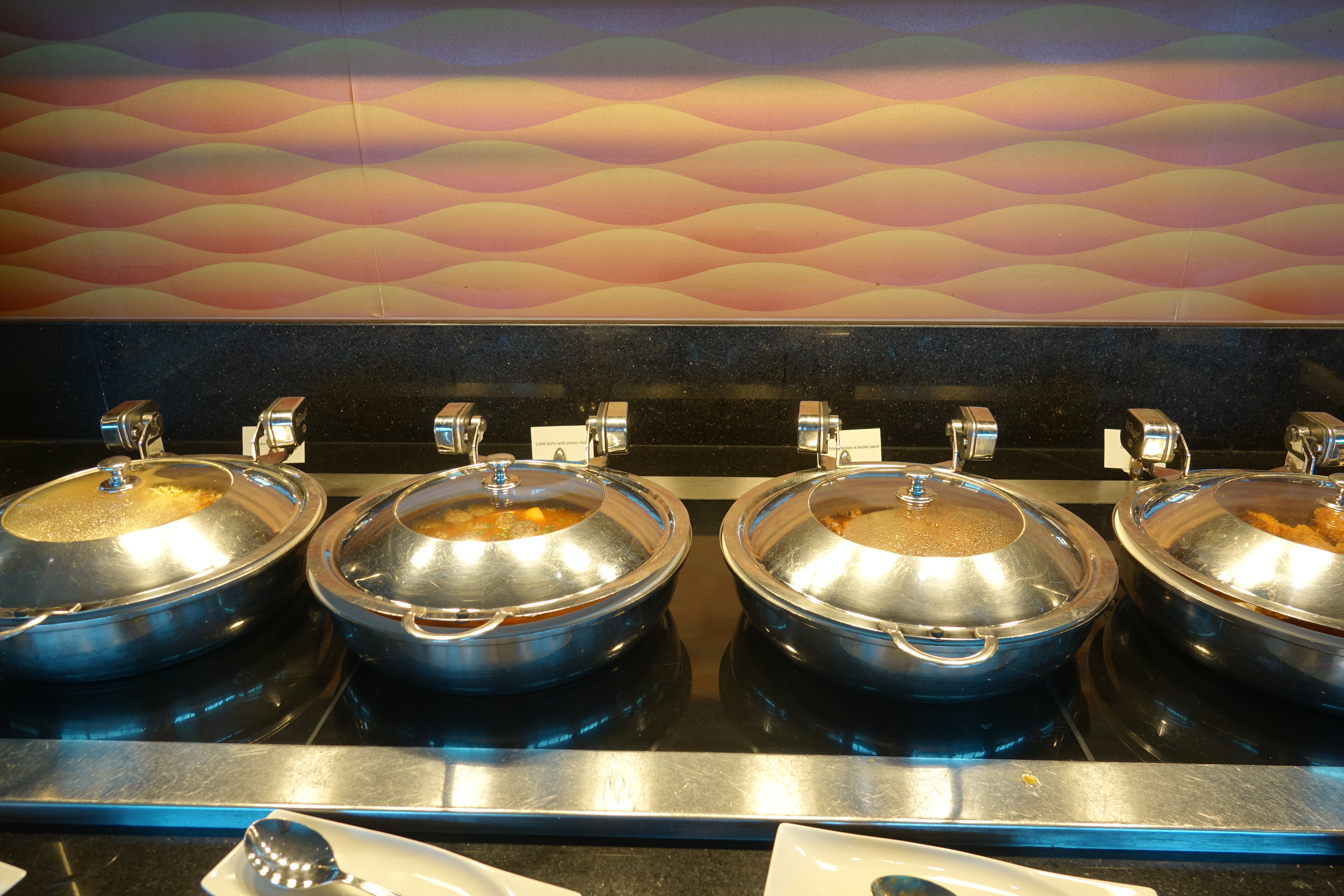 a row of silver bowls with lids on a black surface