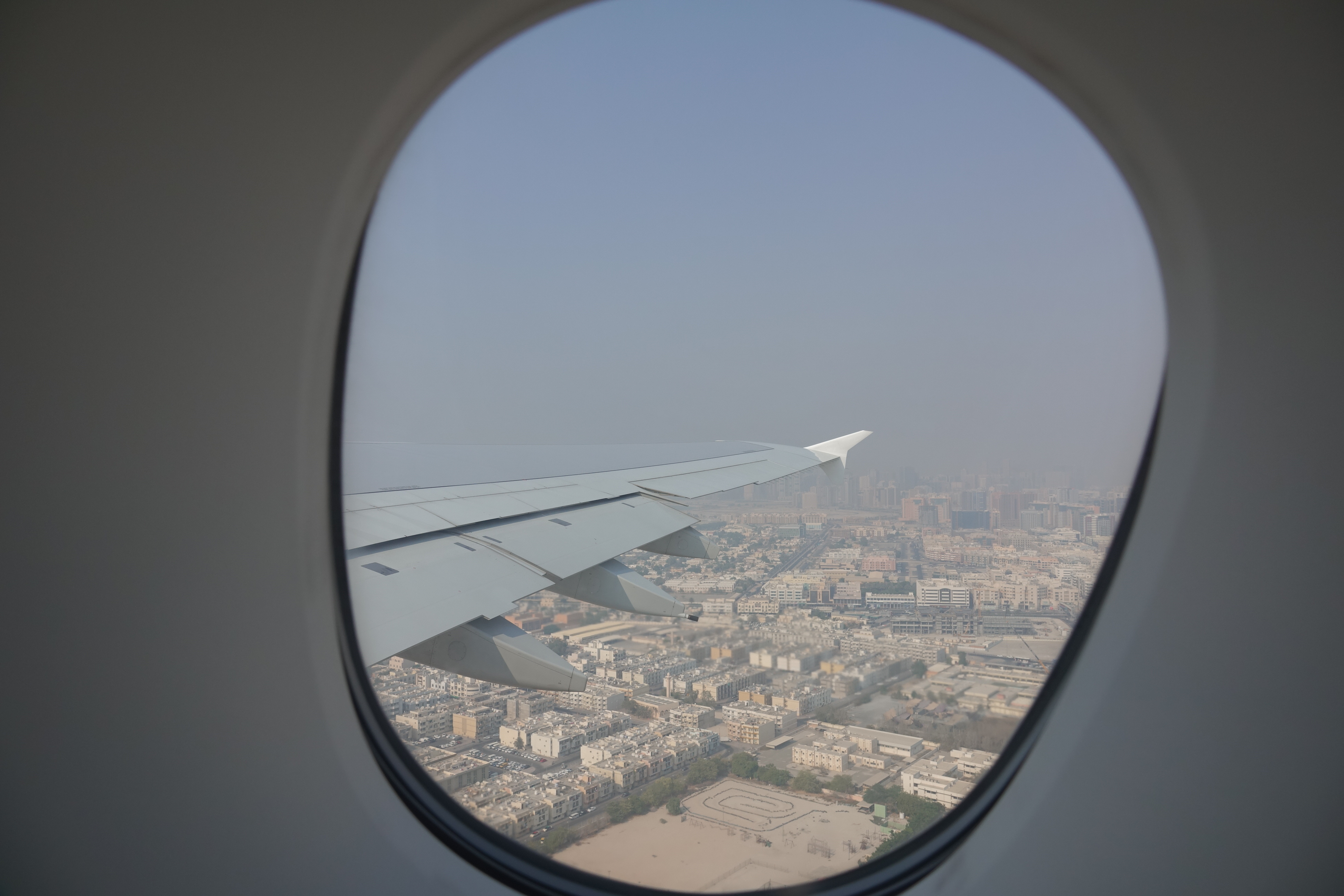 an airplane wing and city view from an airplane window