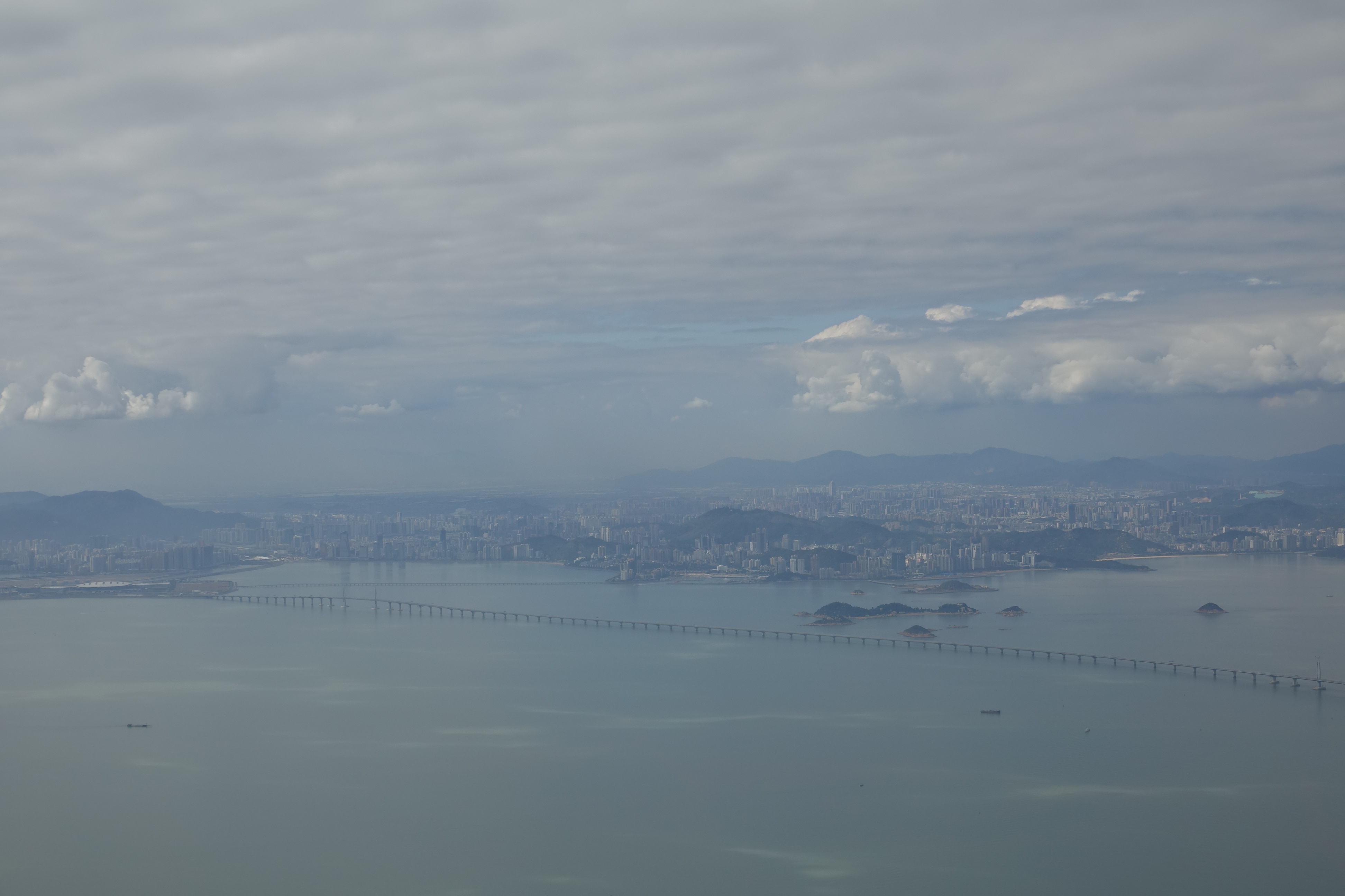 a long bridge over water with a city in the background