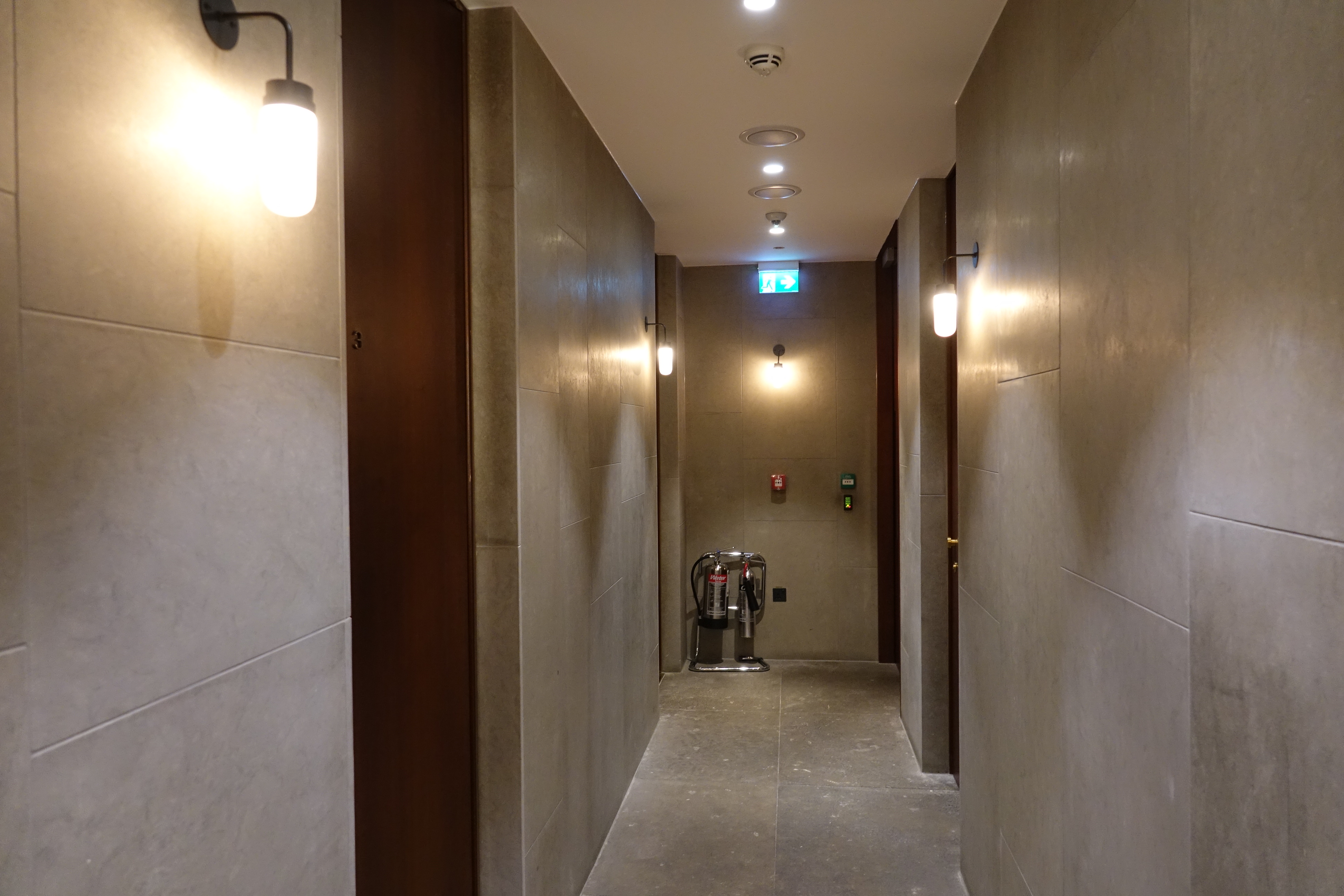 a hallway with lights and a few fire extinguishers