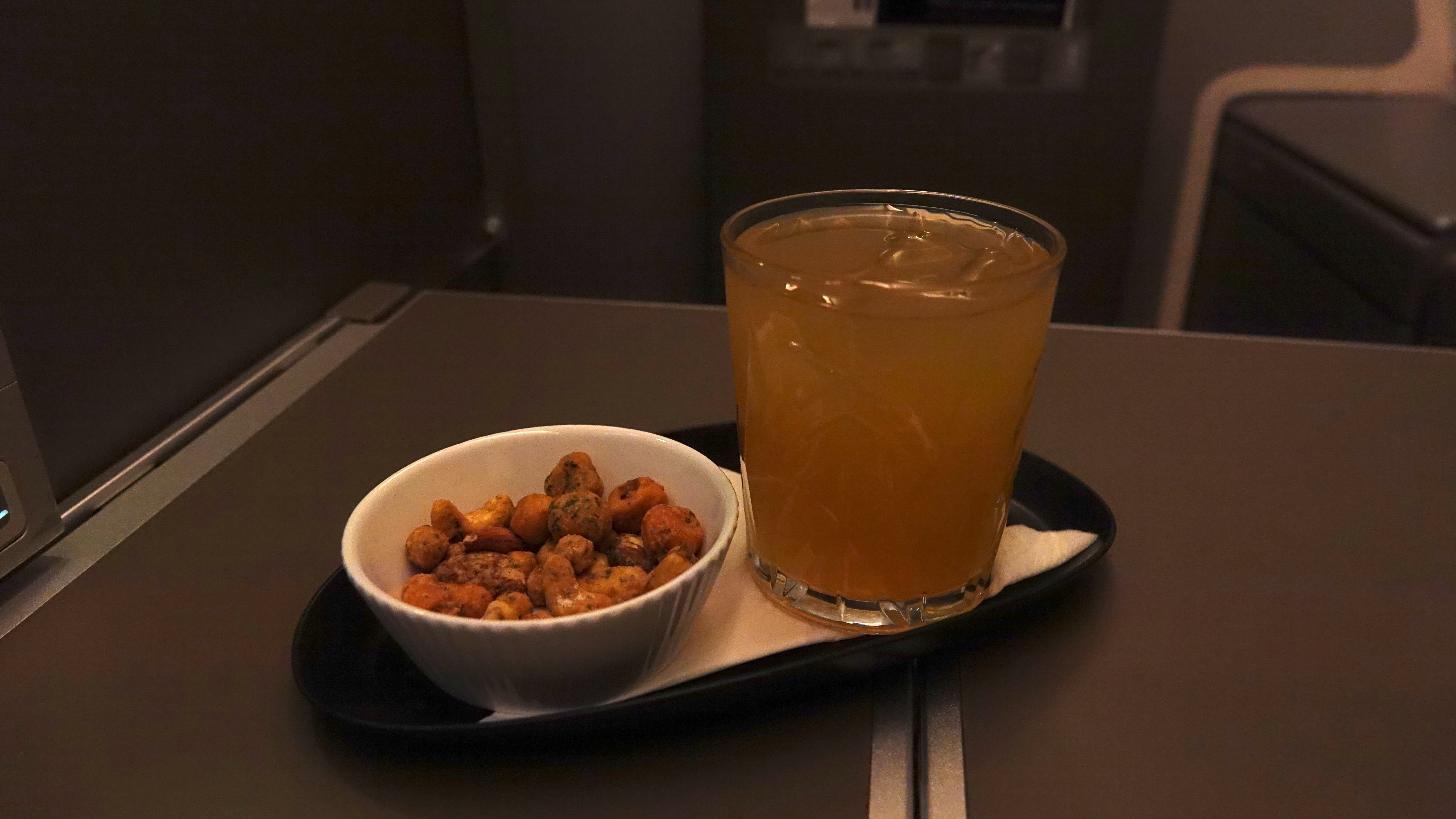 a bowl of nuts and a glass of liquid on a tray