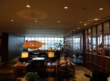 a man sitting in a room with a lamp and a table