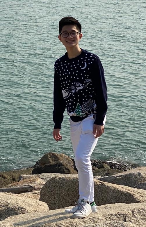 a boy standing on rocks by water