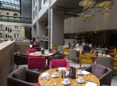 a group of people sitting at tables in a room with a glass ceiling