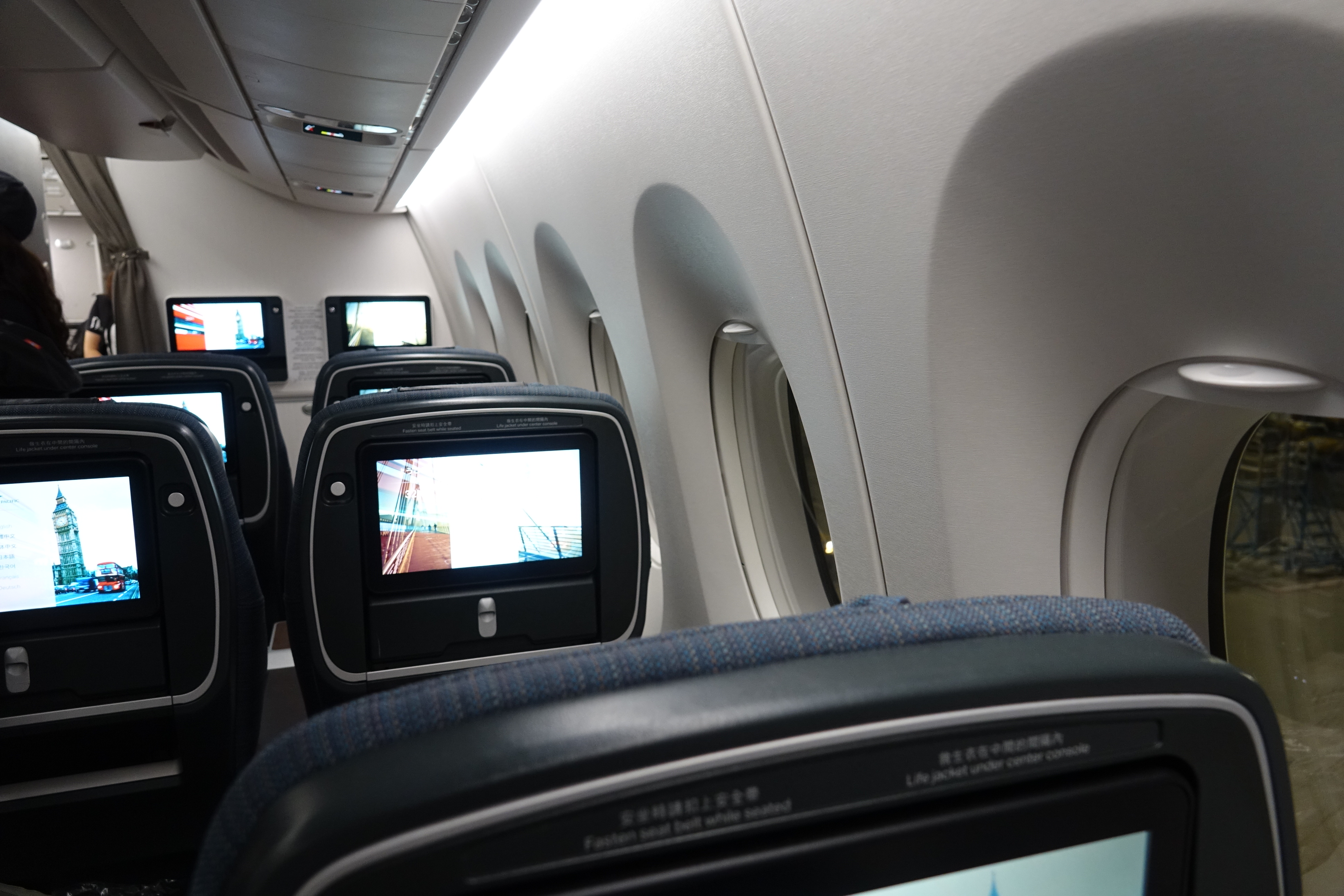 a row of seats with monitors on the side of the plane