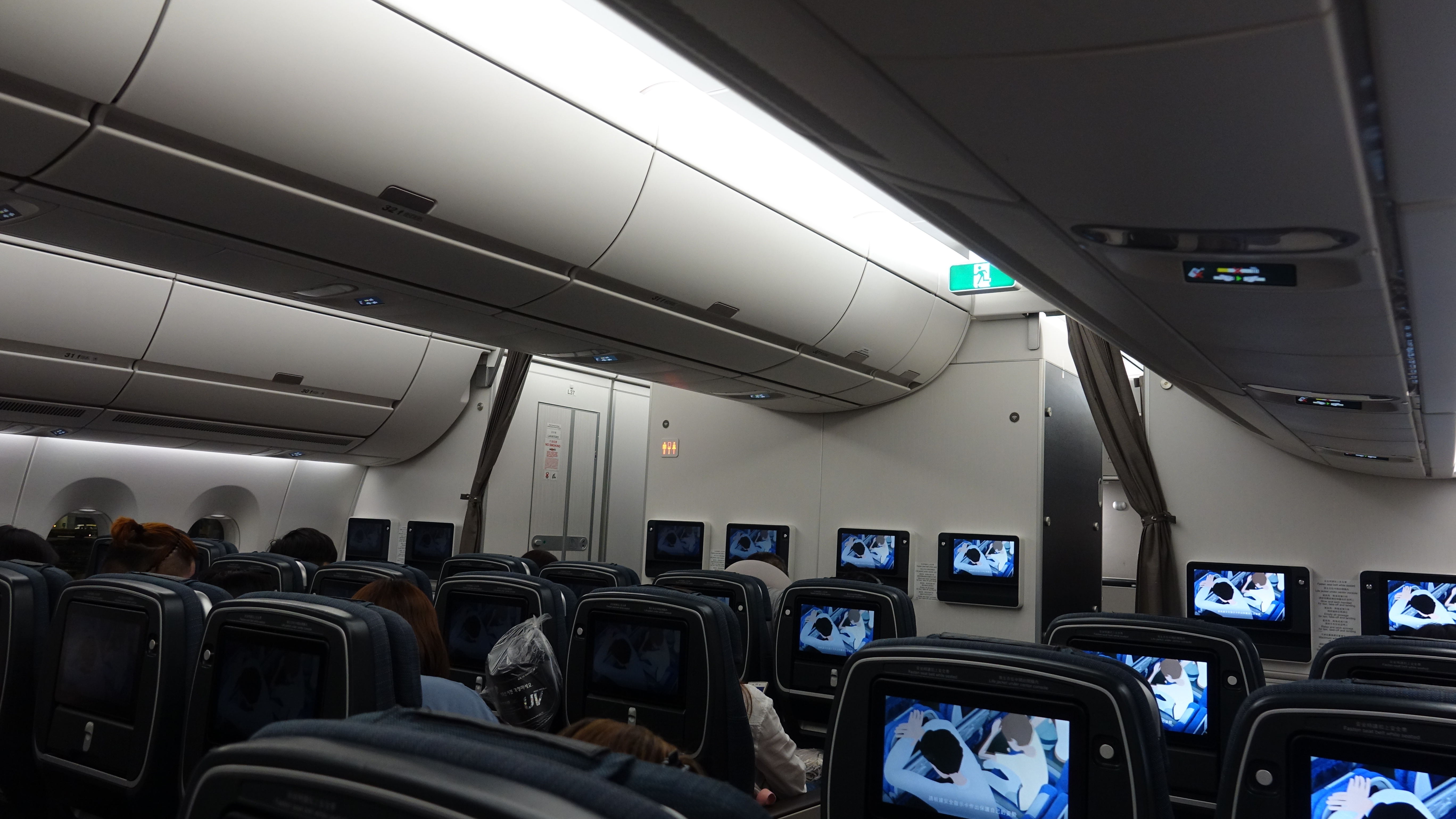 a group of people sitting in an airplane with a television set