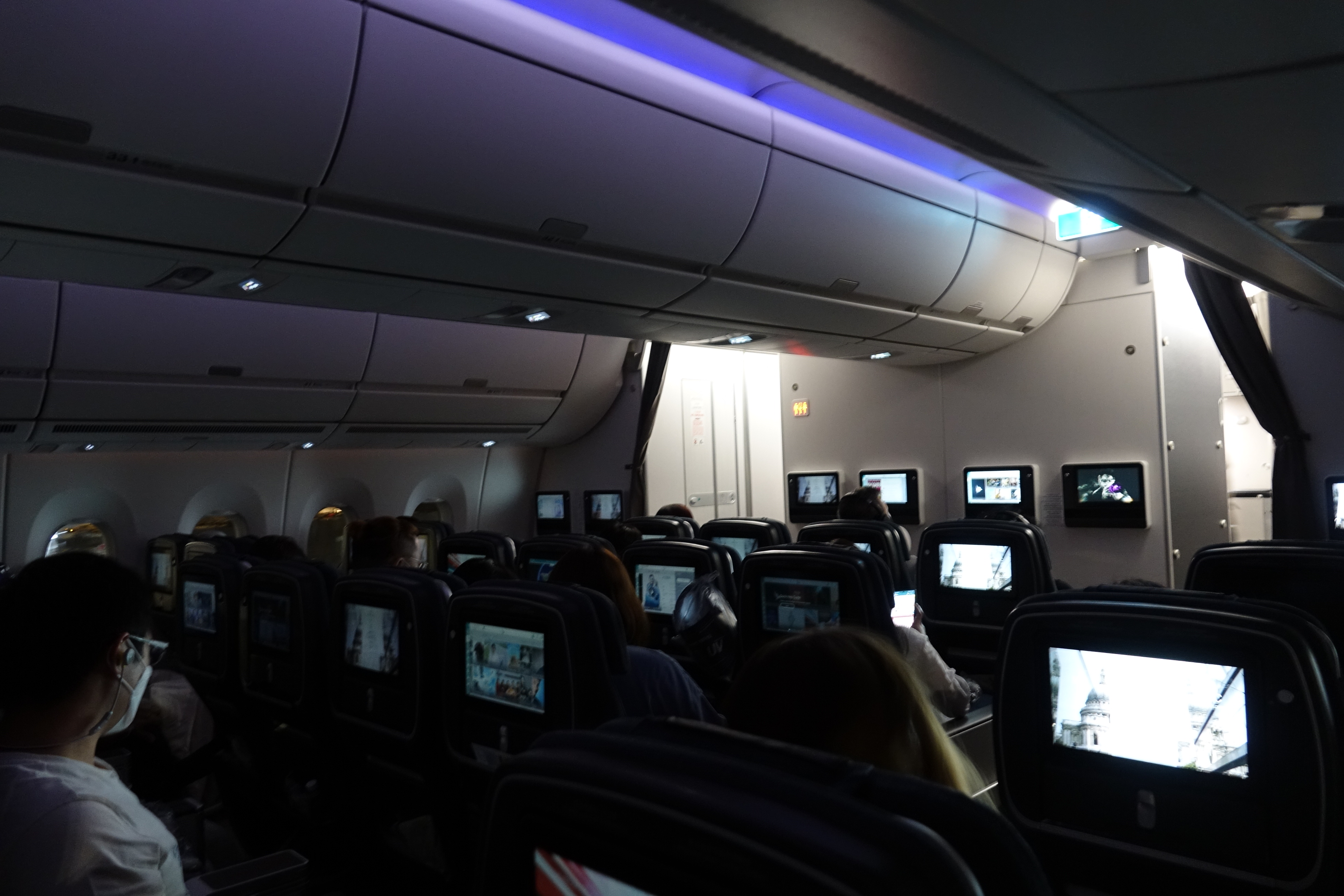 a group of people sitting in an airplane with monitors