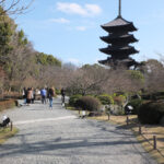 a group of people walking on a path with a pagoda in the background