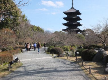 a group of people walking on a path with a pagoda in the background