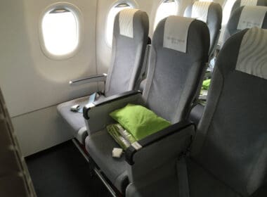 a row of grey seats with a green pillow on the side