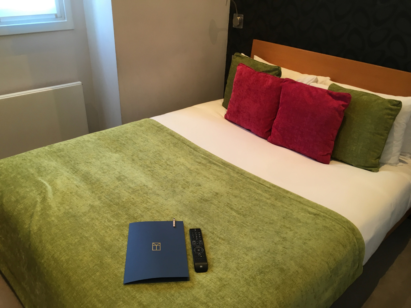 a bed with a remote and a book on it