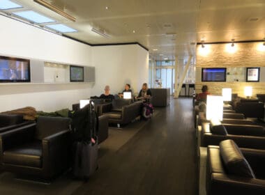 people sitting in a room with black chairs and a television on the wall