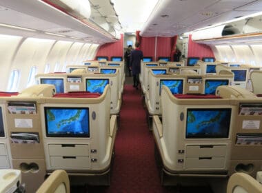 a inside of an airplane with rows of seats and monitors