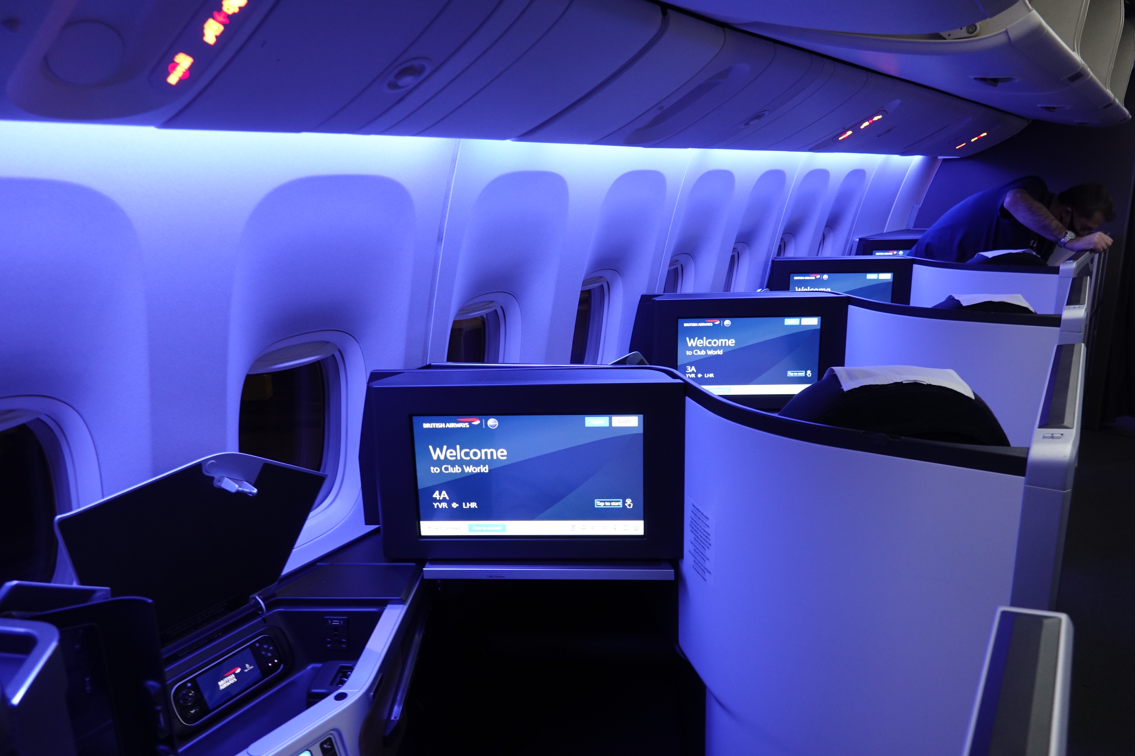 a row of seats with monitors on the side of the plane