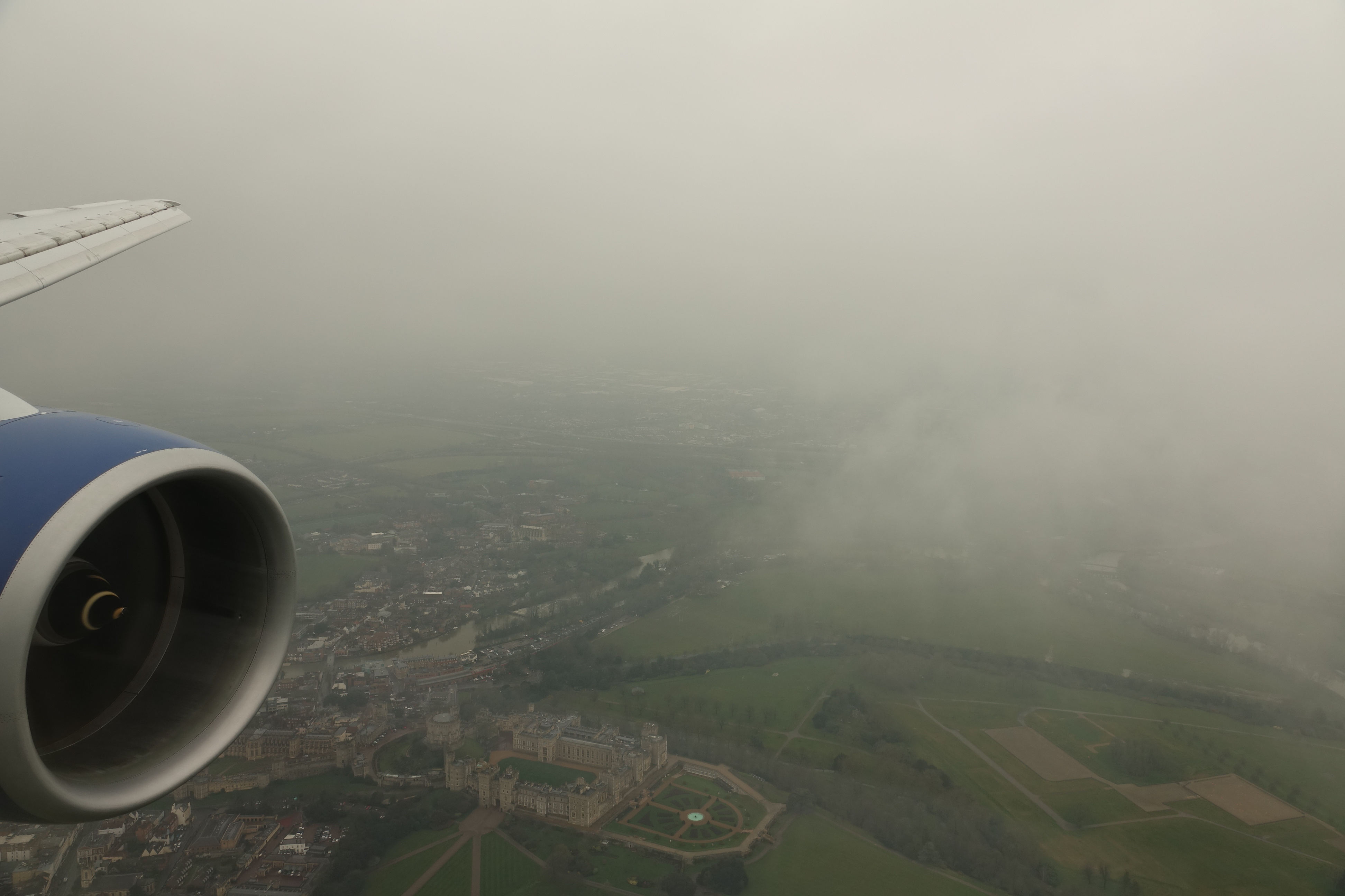 an airplane wing with a view of a city and clouds