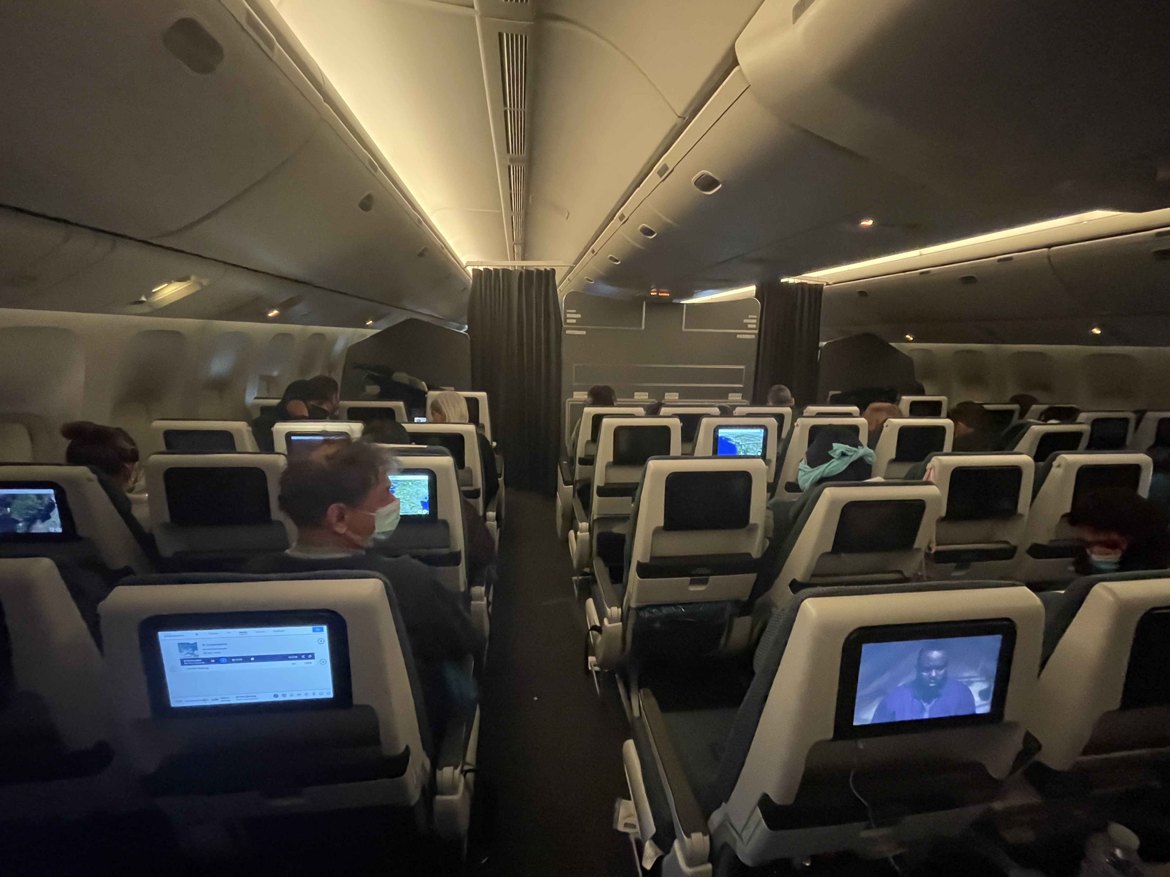 a group of people sitting in an airplane with a computer screen