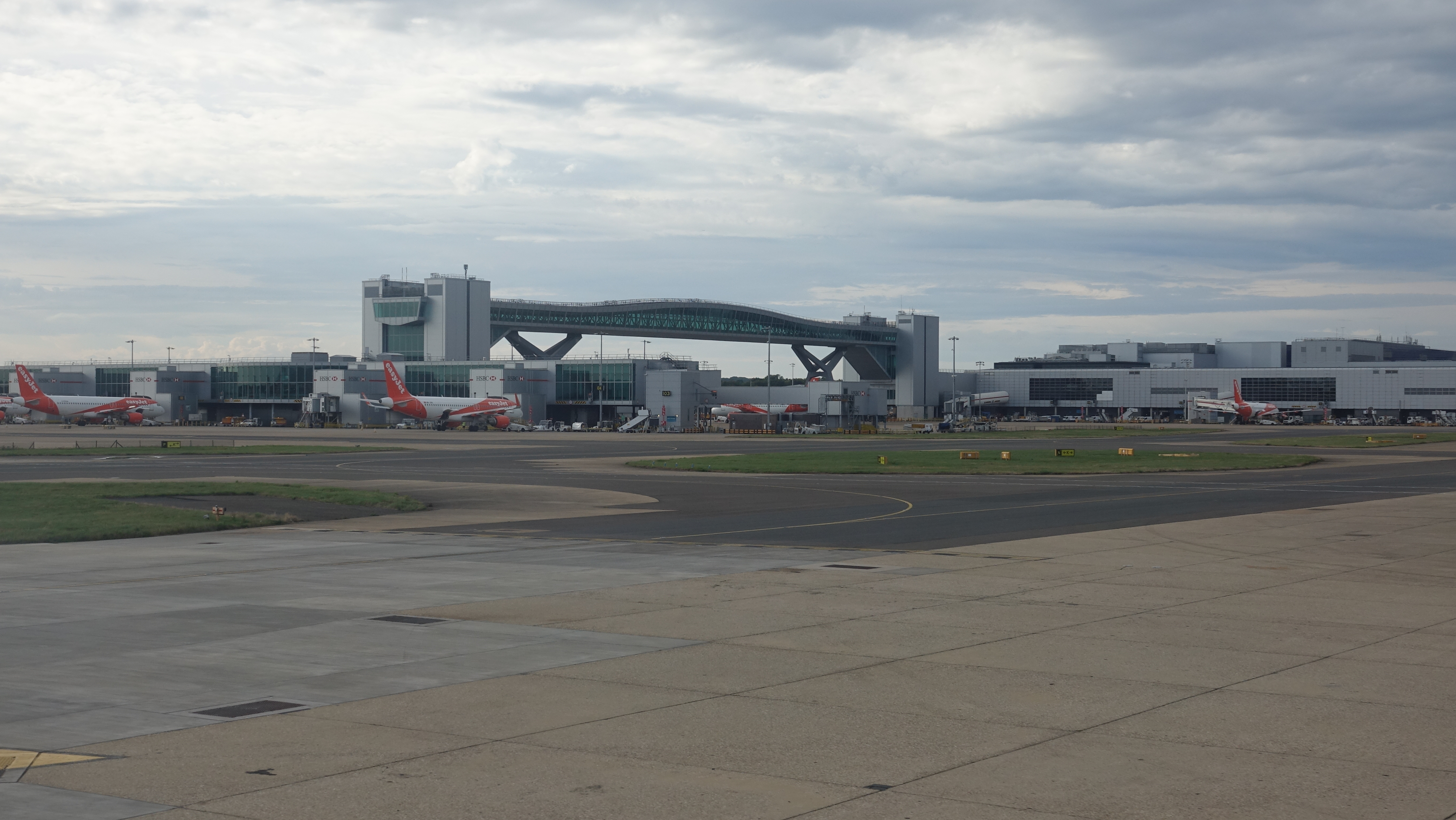 a runway with a bridge over it and a building with planes in the background