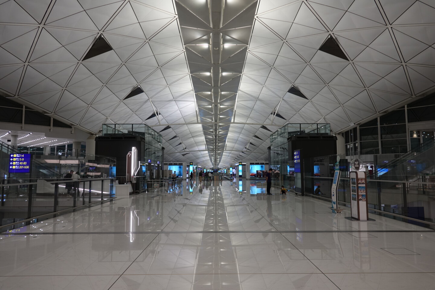 a large white tiled hallway with people walking around