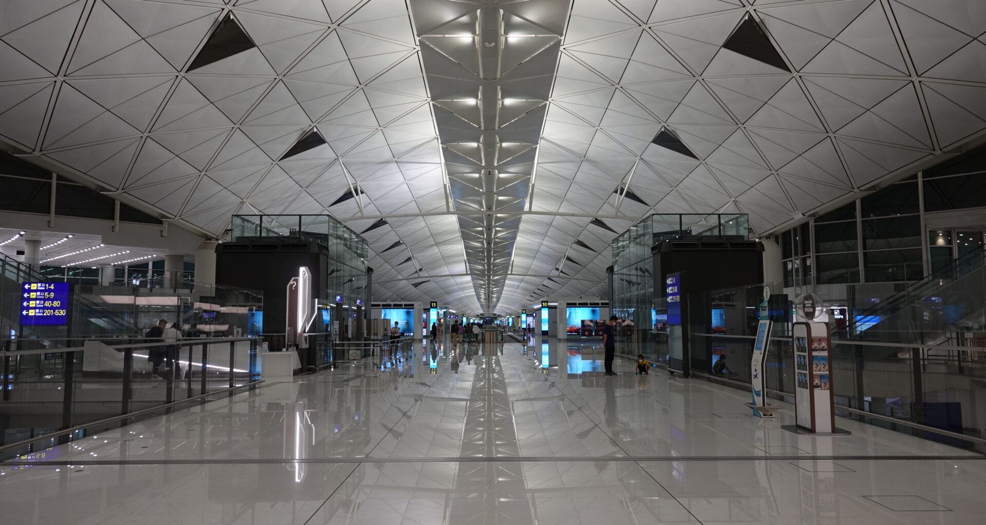 a large white tiled hallway with people walking around