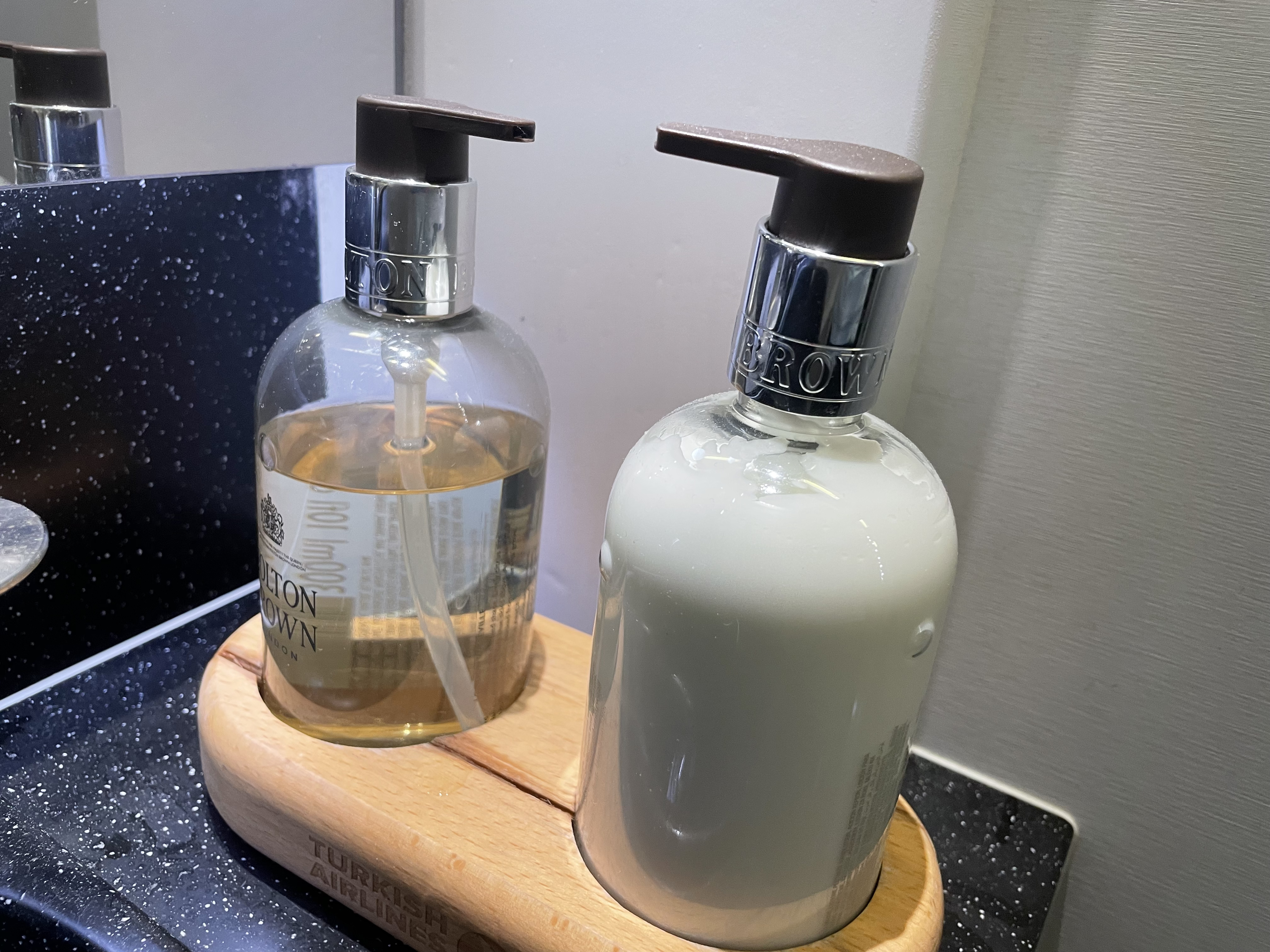 a couple of soap dispensers on a wood holder