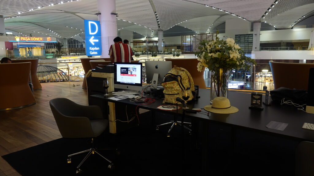 a desk with a computer and a vase of flowers