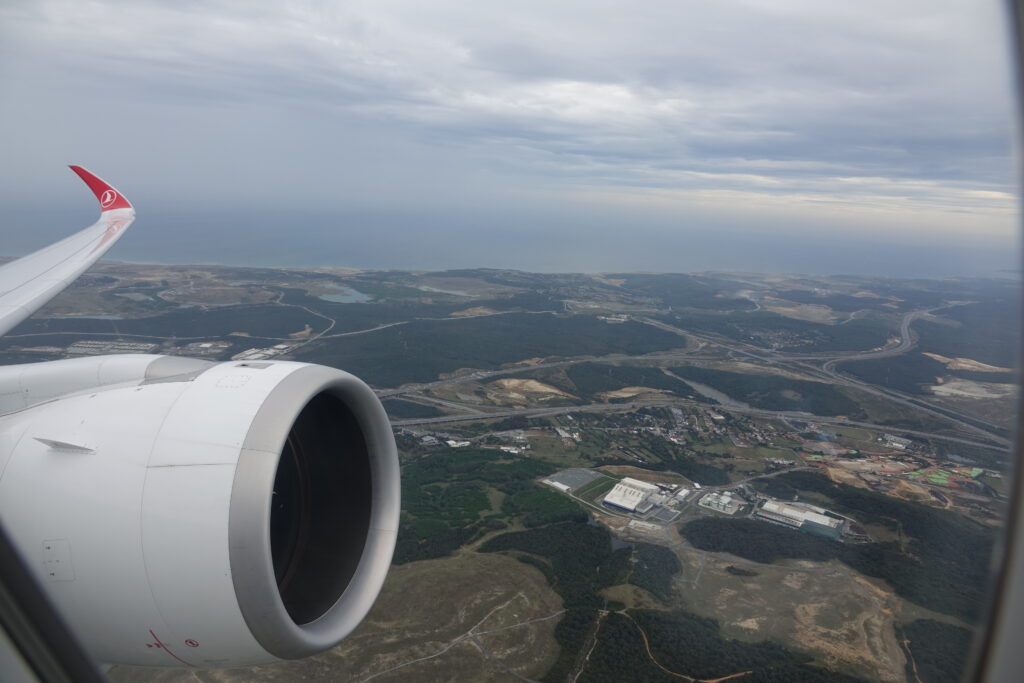 an airplane wing with a large engine and a landscape