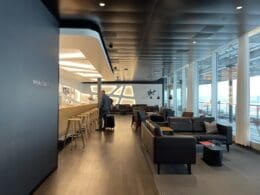 a man with luggage in a room with a bar and chairs