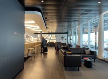 a man with luggage in a room with a bar and chairs