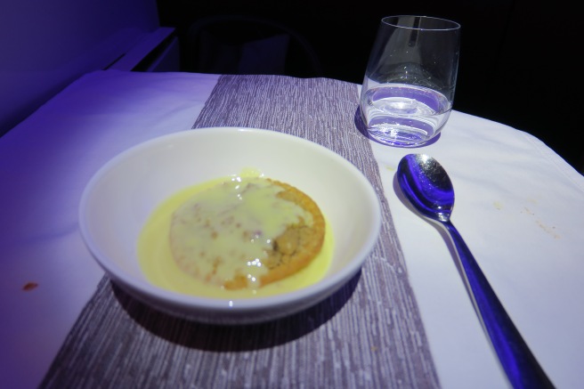 a bowl of food with a spoon and a glass on a table