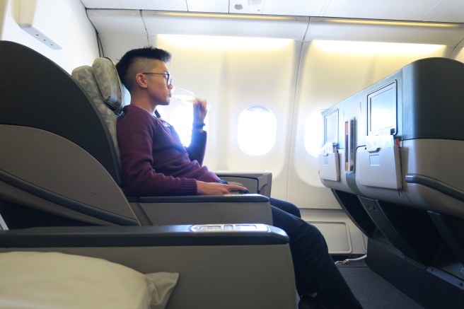 a man sitting in an airplane drinking from a glass