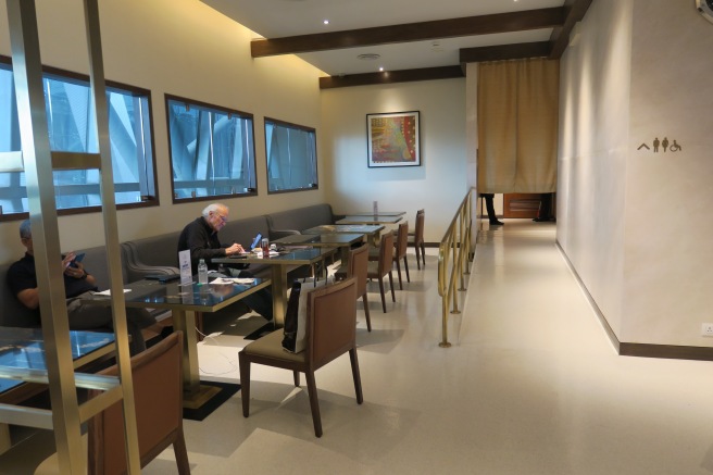 a man sitting at a table in a room with many windows